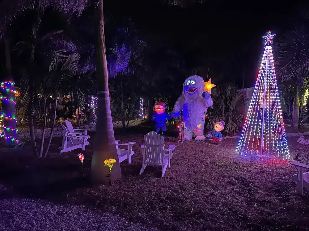 Light-up characters beside a tall cone Christmas tree