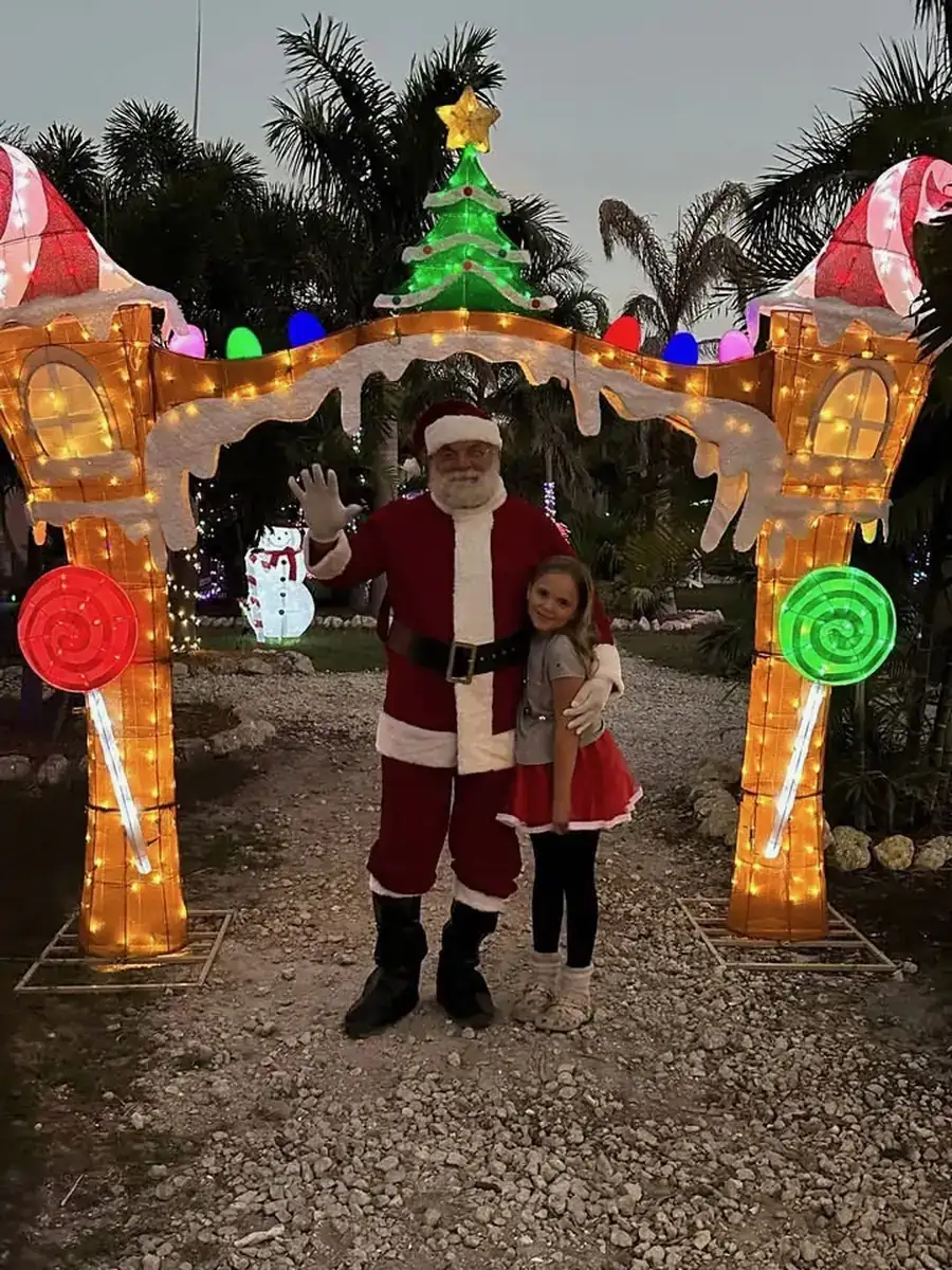 Santa greeting a young visitor under the lit gingerbread arch